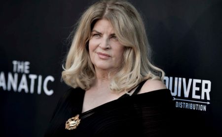 Kirstie Alley in a black dress poses at a movie premiere.